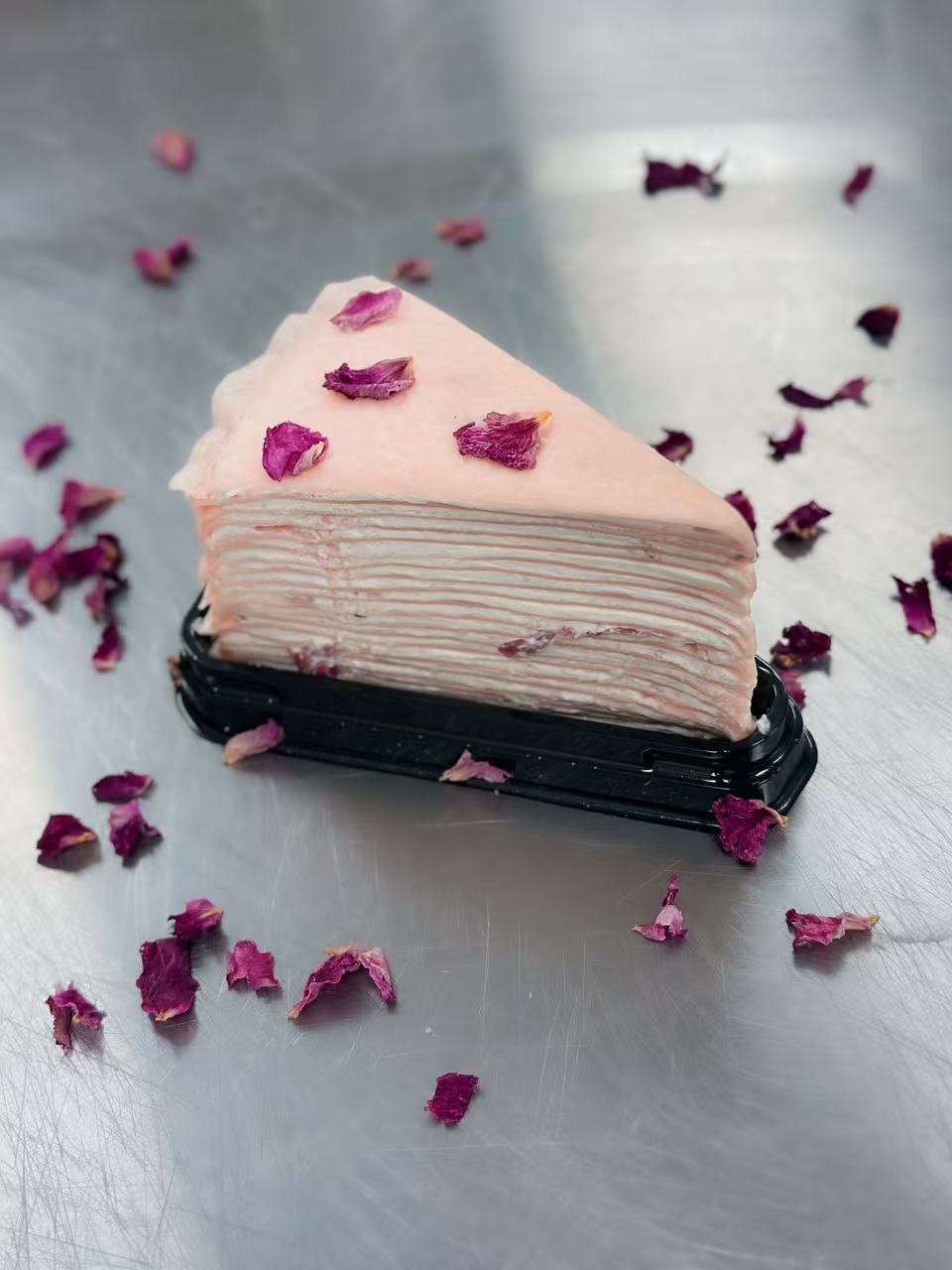 Pink mille crepe cake slice with floral decoration